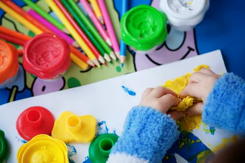 a child's hands playing with yellow playdough