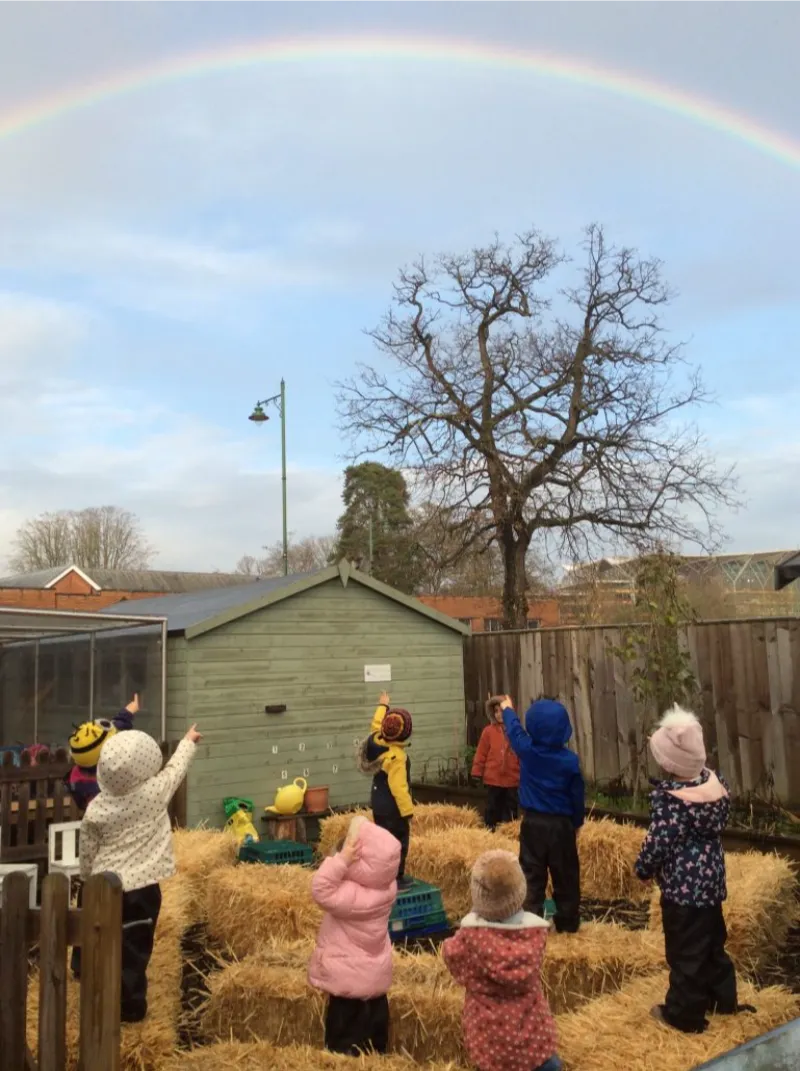 children outside all pointing at a rainbow
